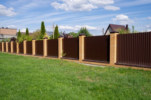 [freepicdownloader.com] brown metal fence with brick posts against sky high wall encloses private area security concept normal