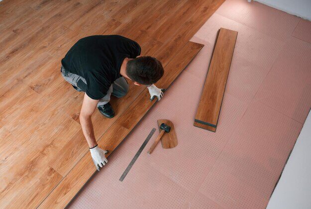 [freepicdownloader.com] top view man is installing new laminated wooden floor normal